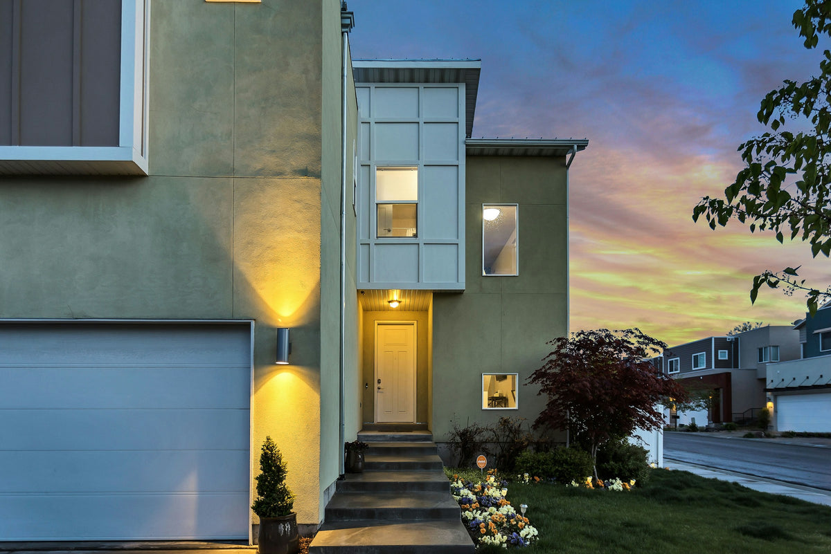 Modern home with a lit doorway under an evening sky